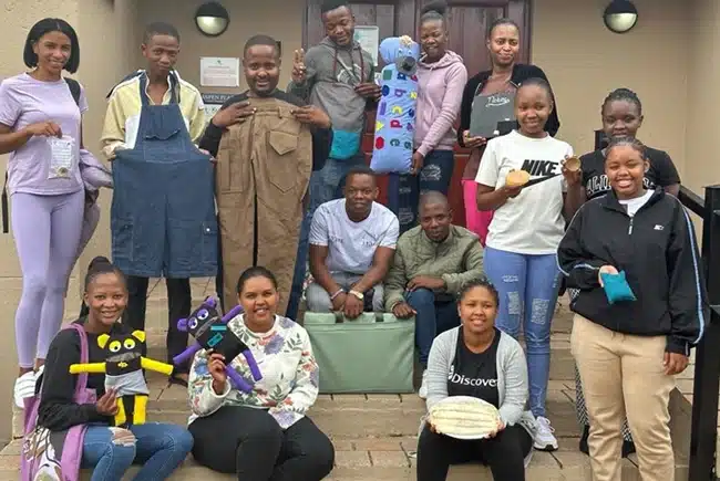 A group of people holding clothing and teddies donated by PnS.